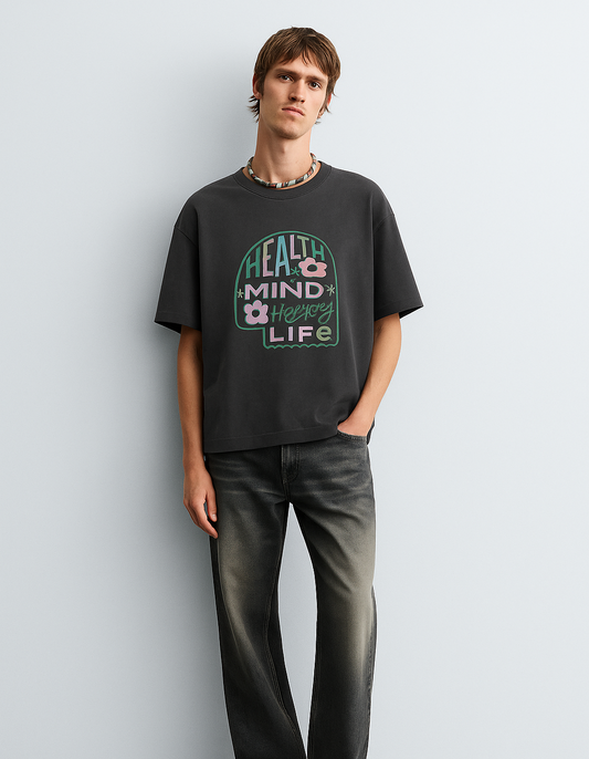 Person wearing a black t-shirt with a graphic design against a plain background